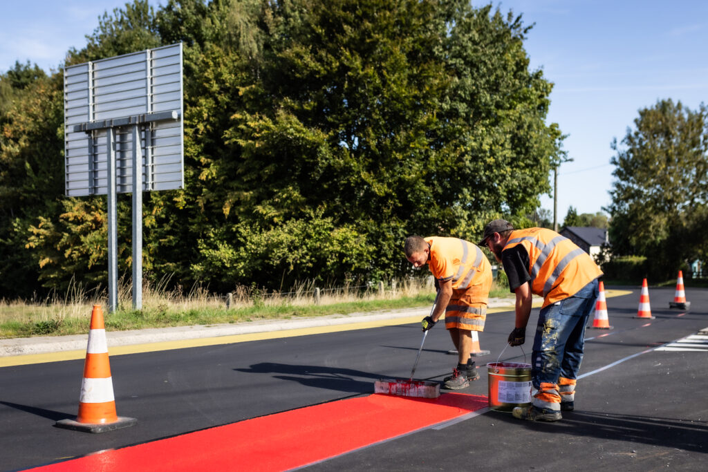 Application manuelle de marquage routier rouge sur chaussée par Lambert Marquage