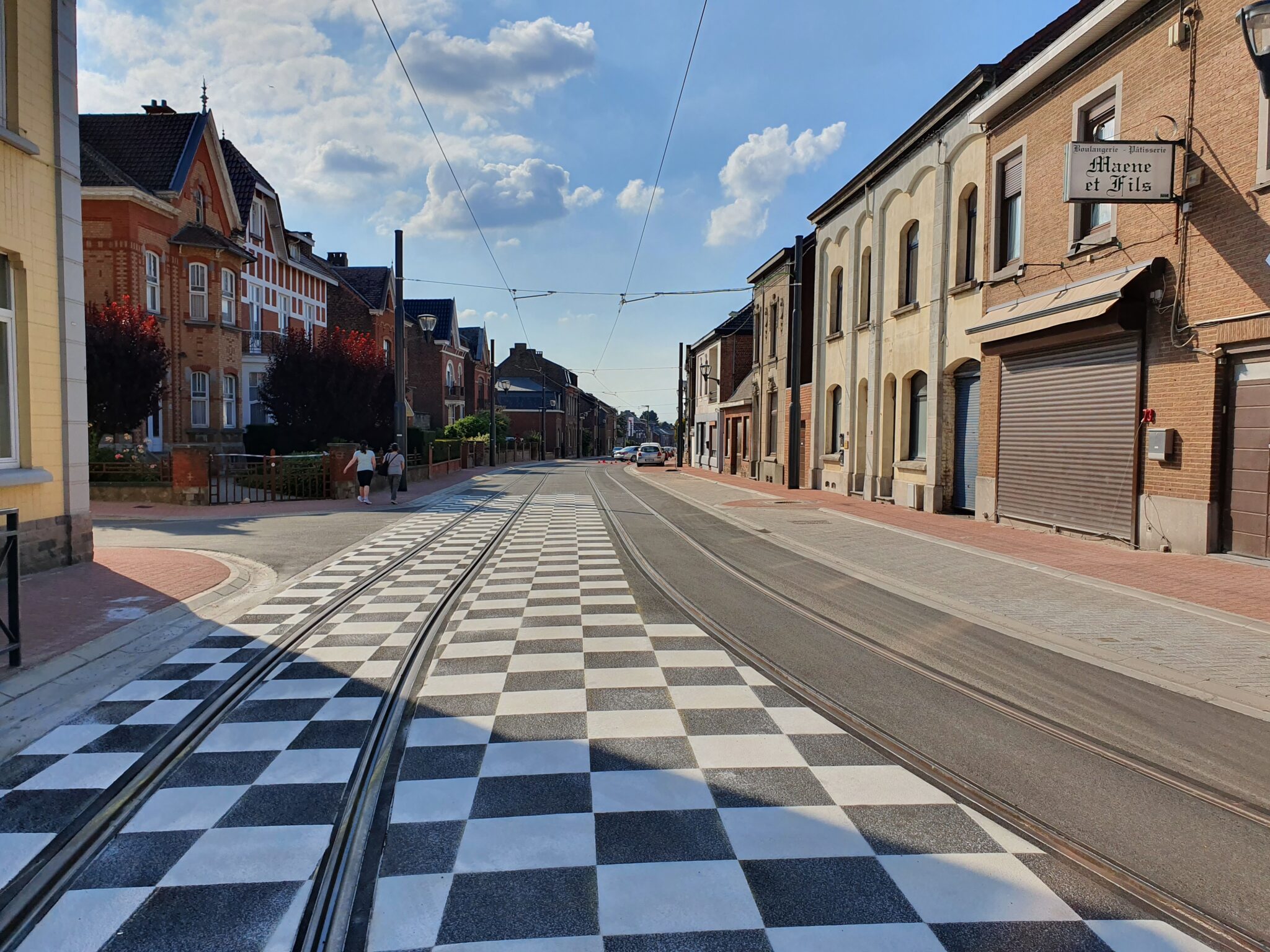Marquage décoratif en damier noir et blanc sur voirie urbaine avec rails de tram par Lambert Marquage