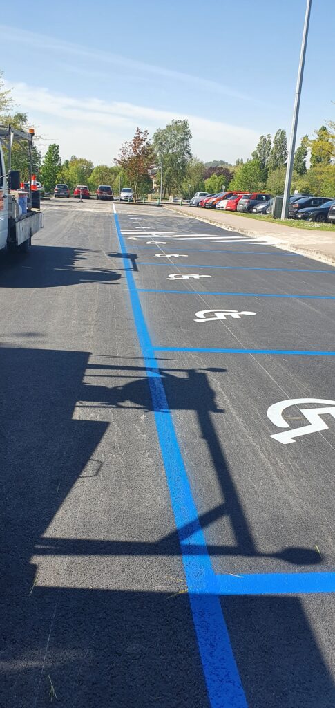 Places PMR avec marquage au sol bleu sur parking extérieur par Lambert Marquage