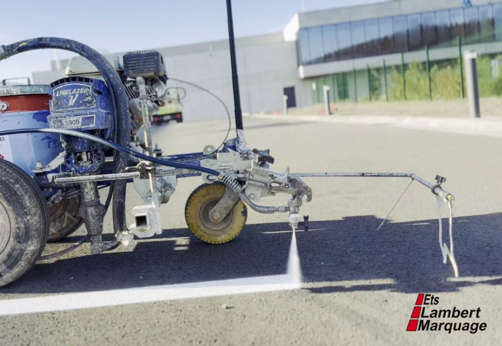 Machine de marquage au sol en train de tracer une ligne blanche sur parking par Lambert Marquage