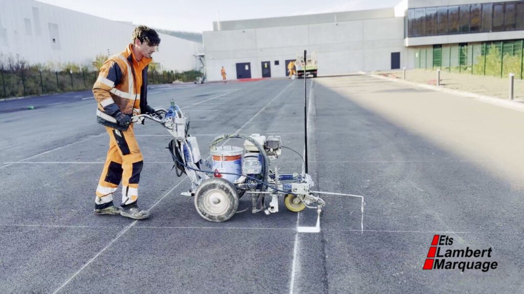 Opérateur en train de tracer des lignes de parking avec une machine de marquage au sol par Lambert Marquage
